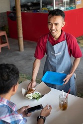 Food stall waiters are happy to serve customers by serving orders on trays at the stall