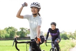 excited young woman riding her road bike with friend
