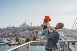 father and daughter travel to turkey. portrait of dad carrying his kid while enjoying the view of beautiful istanbul turkey from the bridge