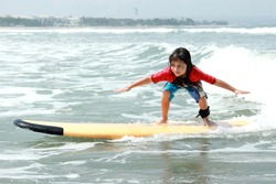 portrait of little boy learn to surf at ocean
