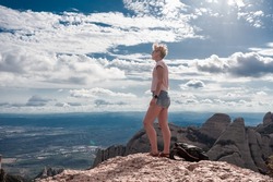 Shot of female hiker on top of Montserrat mountain in Spain. Traveler woman standing on a stone looking at the view.