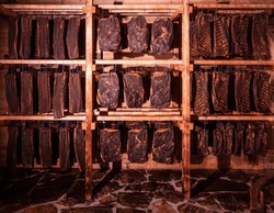 Various specialties of tirolean smoked meat products hang in the drying room
