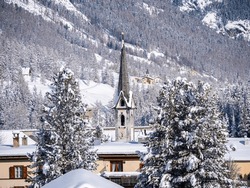Winter view at a bell tower of protestant reformed church in a snow covered village of Cinuos Chel in Engadine, Grisons, Switzerland.