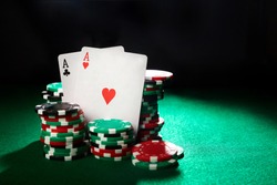 Pair of aces and poker chips on green table. 