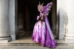 Venice, Veneto, Italy - February 17th, 2023 - Beautiful colored carnival costume on the street in Venice. Carnival of Venice. Woman in purple dress.