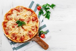 Hot true PEPPERONI ITALIAN PIZZA with salami and cheese. TOP VIEW Tasty traditional pepperoni pizza on board on white wooden table with decoration. Copy space for your logo. Ideal for commercial 