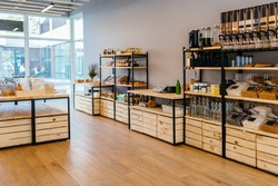 Zero waste shop interior. Wooden shelves with different food goods and personal hygiene or cosmetics products in plastic free grocery store. Eco-friendly shopping at local small businesses