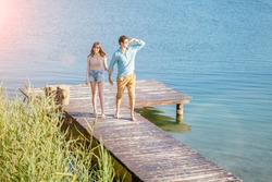 Sun glare. Lovely couple on wooden bridge at summer sunny day. Summer holidays, love, relaxing concept.