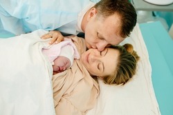 Portrait of happy couple after the delivery of their baby. Family in hospital together.
