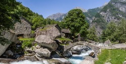 The panoramic image of the ancient roman stone bridge at Puntid high over the Foroglio village in the Maggia valley, Tessin, Switzerland