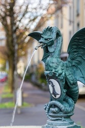 Mythical creature of basilisk on a publich water fountain with Basel city emblem of a black and white crosier, Basel, Switzerland