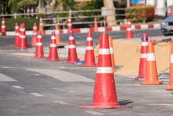 Red and white witches hat cone traffic warning sign barrier applying on busy street, on pedestrian footpath, drive way road under construction