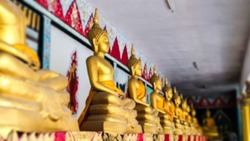 Abstract blurry The line of golden Buddha statue with raw of Brass in the temple. Concept of Buddhist Believe. Thailand Culture and Traditional. Buddha is sign of the calm and meditation.