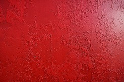 Abstract background of dark red or maroon color. Decorative plaster or wall painted with red paint over an old layer of paint. Old rusty metal painted red or Marsala color