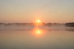 Sunrise on a forest lake. Beautiful foggy morning nature landscape. Calm scene. Dawn, mist, calm water