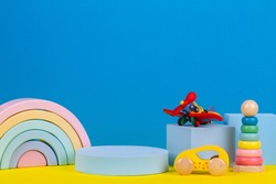 Babby kid toy background. Composition of colorful educational toys and geometric shapes podium, platform on blue and yellow background. Front view