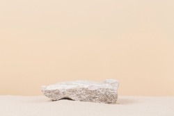 Grungy grey concrete stone platform podium for cosmetics or products on white beach sand background. Front view