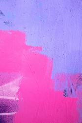 Purple paint strokes and smudges on an pink painted wall background. Abstract wall surface with part of graffiti. Colorful drips, flows, streaks of paint and paint sprays