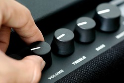  man's hand is adjusting the music volume from the amplifier.