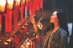 A beautiful asian woman enjoyed looking at red lamps and wishes in Chinese temple
