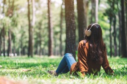 A beautiful asian woman enjoy listening to music with headphone with feeling happy and relaxed in the park