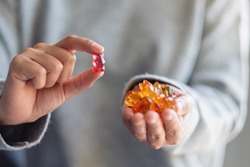 Closeup image of a woman holding and looking at a red jelly gummy bear 
