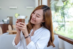 Portrait image of a beautiful young asian woman holding and drinking iced coffee