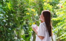 Portrait image of a beautiful young asian woman drinking coffee and relaxing with nature views
