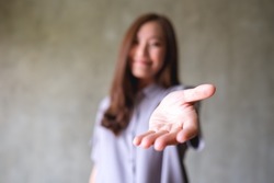 Blurred image of a young woman with reaching hand or giving hand to someone