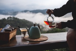 Closeup of a woman making drip coffee to drink with a beautiful mountain and nature view in background