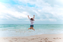 A woman jumping on the beach in front of the sea with feeling happy and freedom
