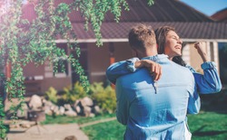 Rear View Of Loving Couple Walking Towards House. Young smiling couple showing keys to new home hugging. Couple in love. Background. Love concept. Happiness. Lifestyle. Emotion. Concept. Lovely.
