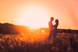 Romantic couple standing  and kissing on background summer meadow sunset