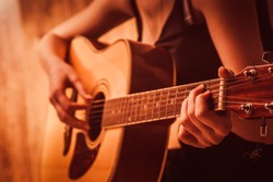 woman's hands playing  acoustic guitar, close up