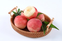 Fresh Peach fruits with leaves in a basket on a white.Bite of a peach fruit.