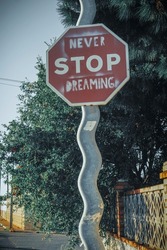 Traffic sign of stop with the message never stop dreaming on a corrugated pole