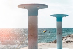 Stone columns with public showers in Sitges Beach, Barcelona, Spain. Photography with light effect.