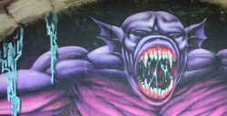 Fragment of graffiti drawings. The old wall decorated with paint stains in the style of street art culture. Purple scary monster