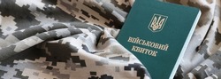 Ukrainian military ID on fabric with texture of pixeled camouflage. Cloth with camo pattern in grey, brown and green pixel shapes with Ukrainian army personal token close up.