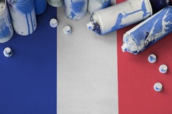 France flag and few used aerosol spray cans for graffiti painting. Street art culture concept, vandalism problems