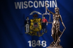 Wisconsin US state flag with statue of lady justice and judicial scales in dark room. Concept of judgement and punishment, background for jury topics