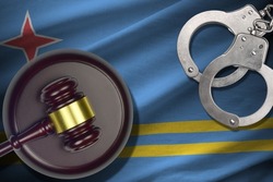Aruba flag with judge mallet and handcuffs in dark room. Concept of criminal and punishment, background for guilty topics