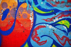 Fragment of an old colored graffiti drawing on the wall. Background image as an illustration of street art, vandalism and wall painting with aerosol paint