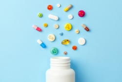 Vitamin tablets. Bottle with colored pills on blue background. Multivitamins.