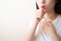 Young ill female have a cough and sore throat over white background. Causes of cough include pneumonia, bronchitis, allergy, asthma, COPD, TB or respiratory tract infection. Copy space. Health care.