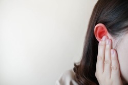 Young woman suffering from ear pain and tinnitus. Cause of earache includes otitis, earwax buildup, a foreign object in the ear, sinus infection or changes in air pressure. Ear disease concept.