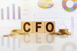 CFO the word on wooden cubes, cubes stand on a reflective surface, in the background is a business diagram. Business and finance concept