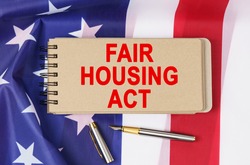 Law and order concept. Against the background of the flag of the United States of America lies a notebook with the inscription - FAIR HOUSING ACT
