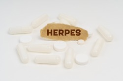 Medicine and health concept. On a white background pills and a piece of paper with the inscription - HERPES