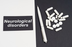 Medical concept. On a white and black surface are pills, a pen and a sign with the inscription - Neurological Disorders